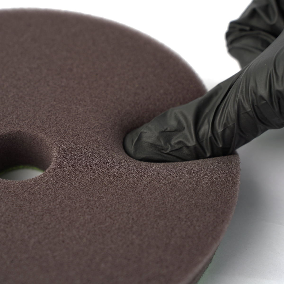 Brown foam pad with a black glove on a white background