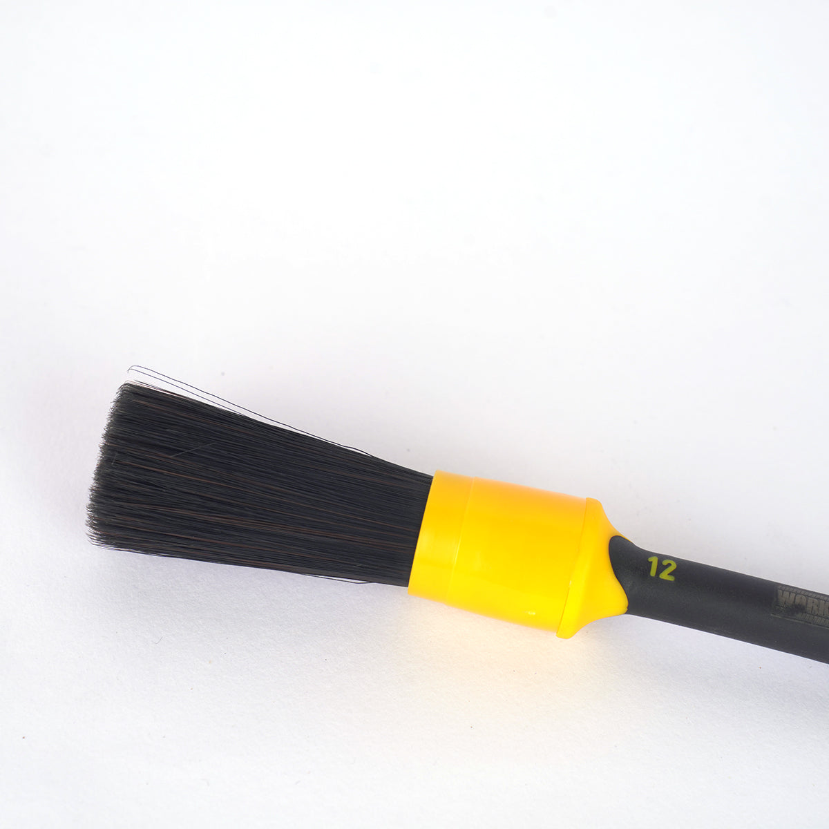 Paint brush with black bristles and yellow handle on a white background