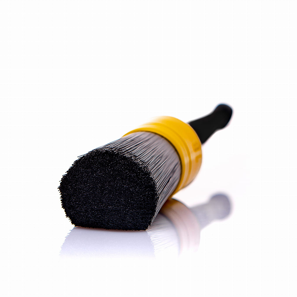 Cleaning brush with black bristles and yellow handle on a white background