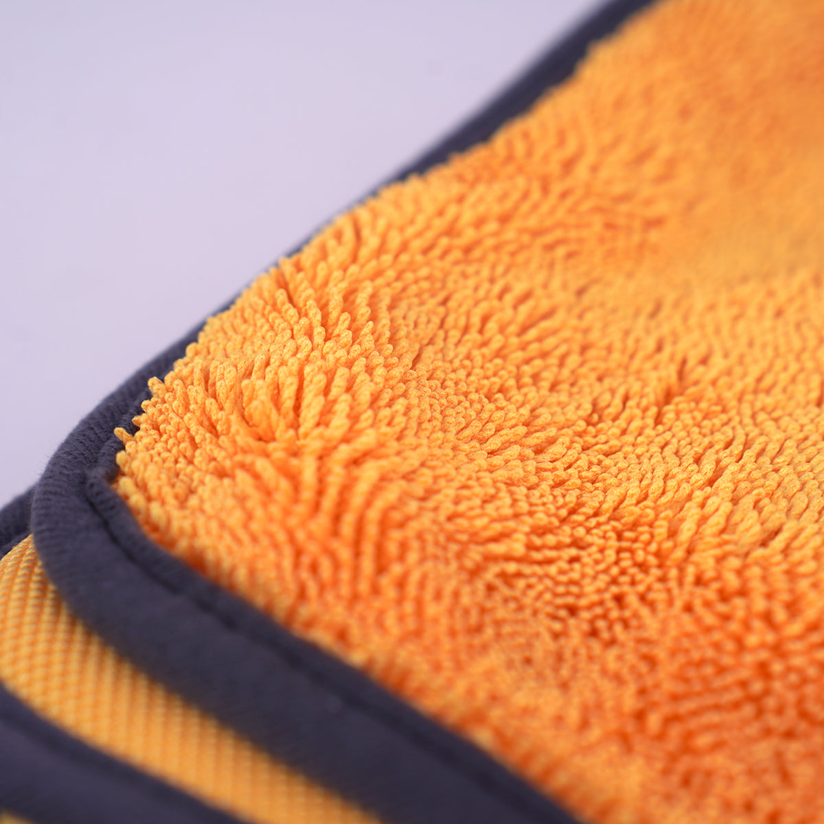 Close-up of an orange microfiber cloth with a purple background
