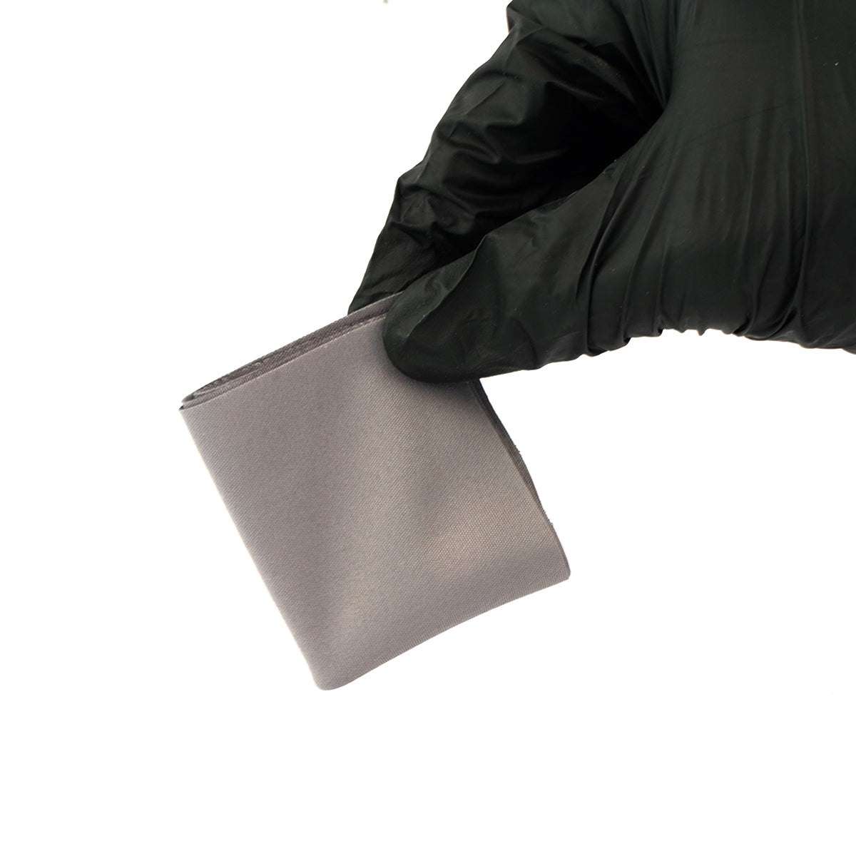 Hand wearing a black glove holding a metallic square object on a white background