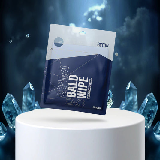 GYEON Q2M Bald Wipe packaging on a white pedestal with crystal-like structures against a dark blue background