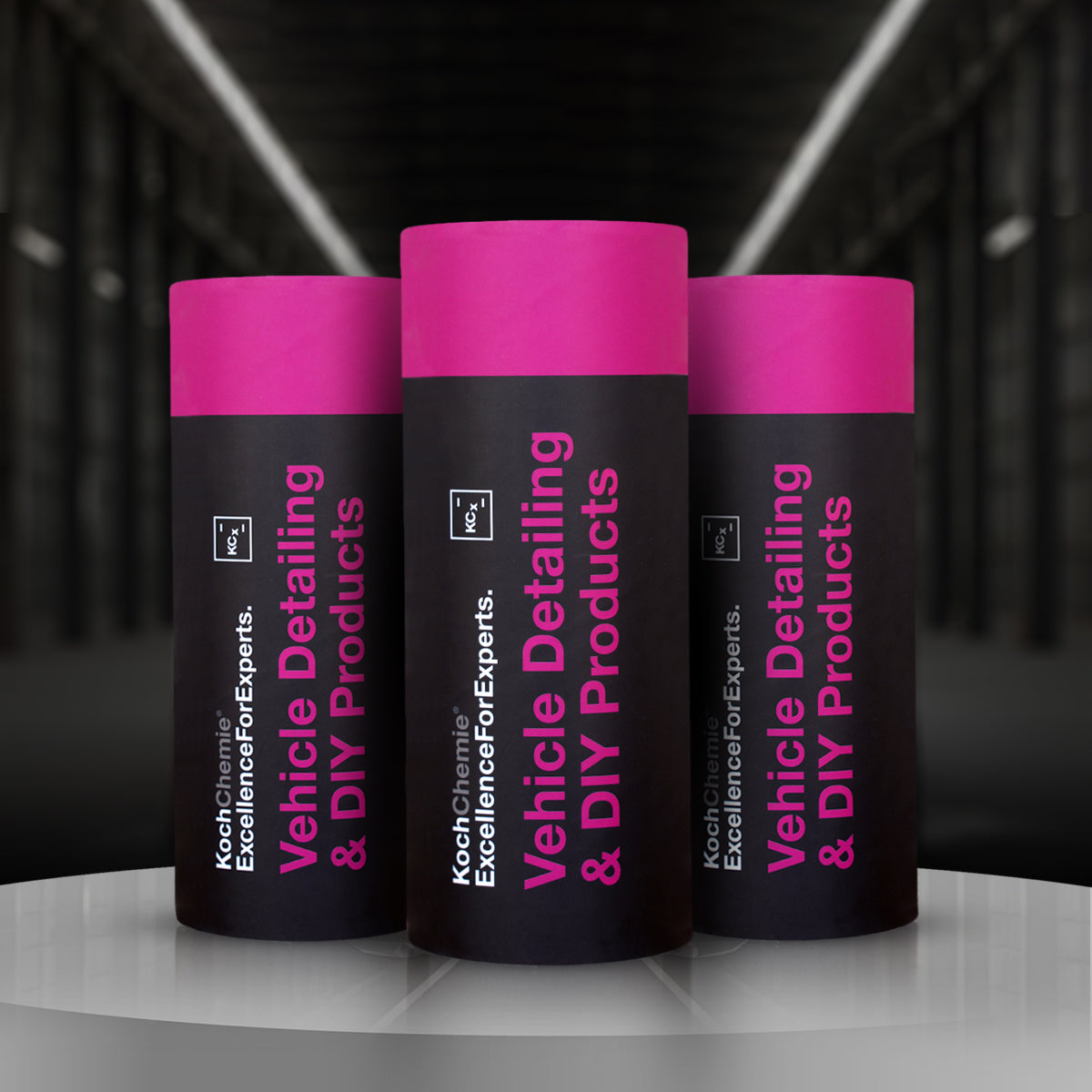 Three tubes of Koch Chemie car tissue with pink caps and black body, placed against a dark background with reflective floor.