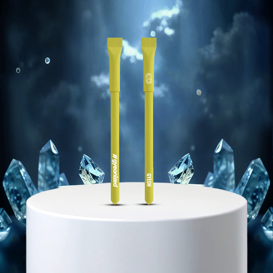 Paper Pen Yellow - Two yellow toothbrushes on a white platform with blue crystal-like structures in the background