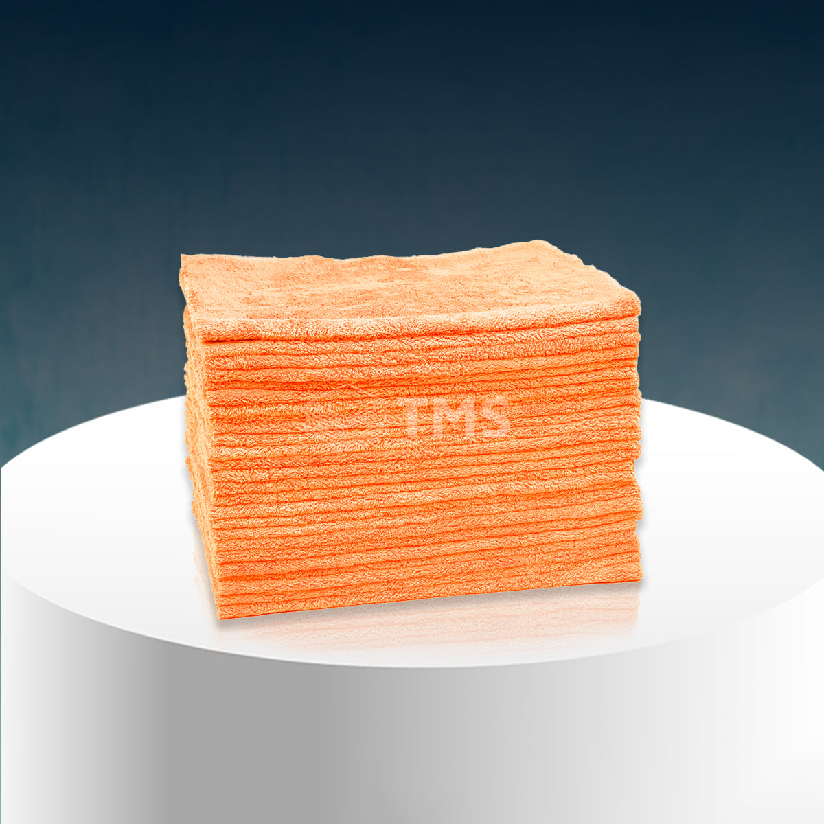 An orange microfiber towel on a white cylindrical stand against a dark background.