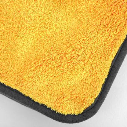 Close-up of a yellow microfiber cloth with a black border on a gray background