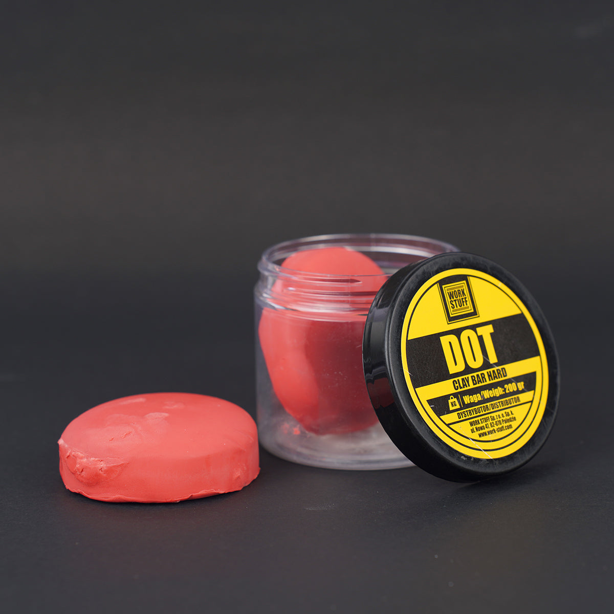Red clay bar with a black and yellow labeled container on a dark background