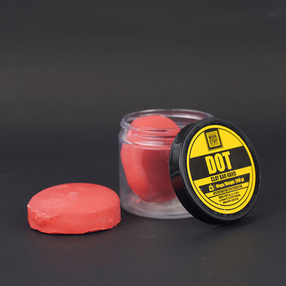 Red clay bar with a black and yellow labeled container on a dark background