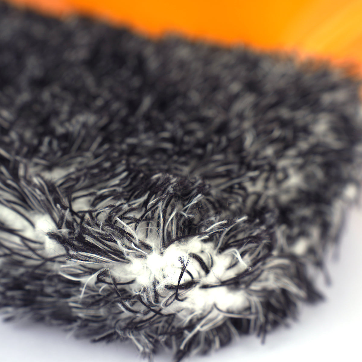 Close-up of a textured black and white fabric with an orange background