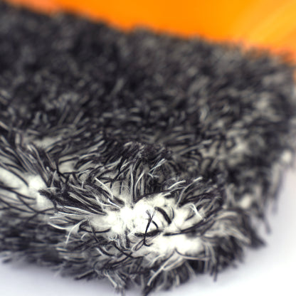 Close-up of a textured black and white fabric with an orange background