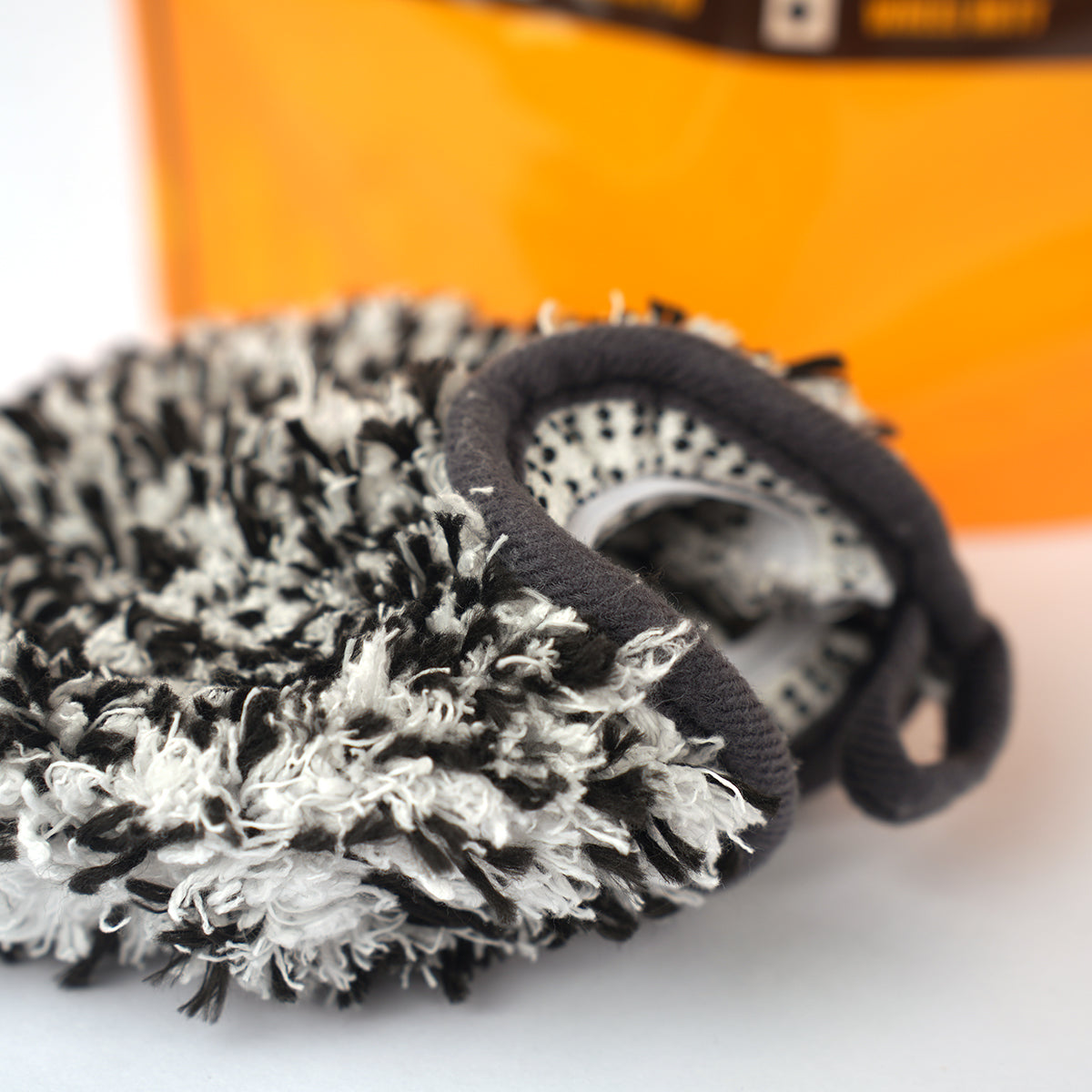 Black and white textured scrubber on a white surface with an orange background